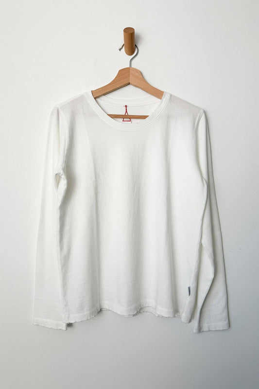 White long-sleeve shirt on a wooden hanger against a white background