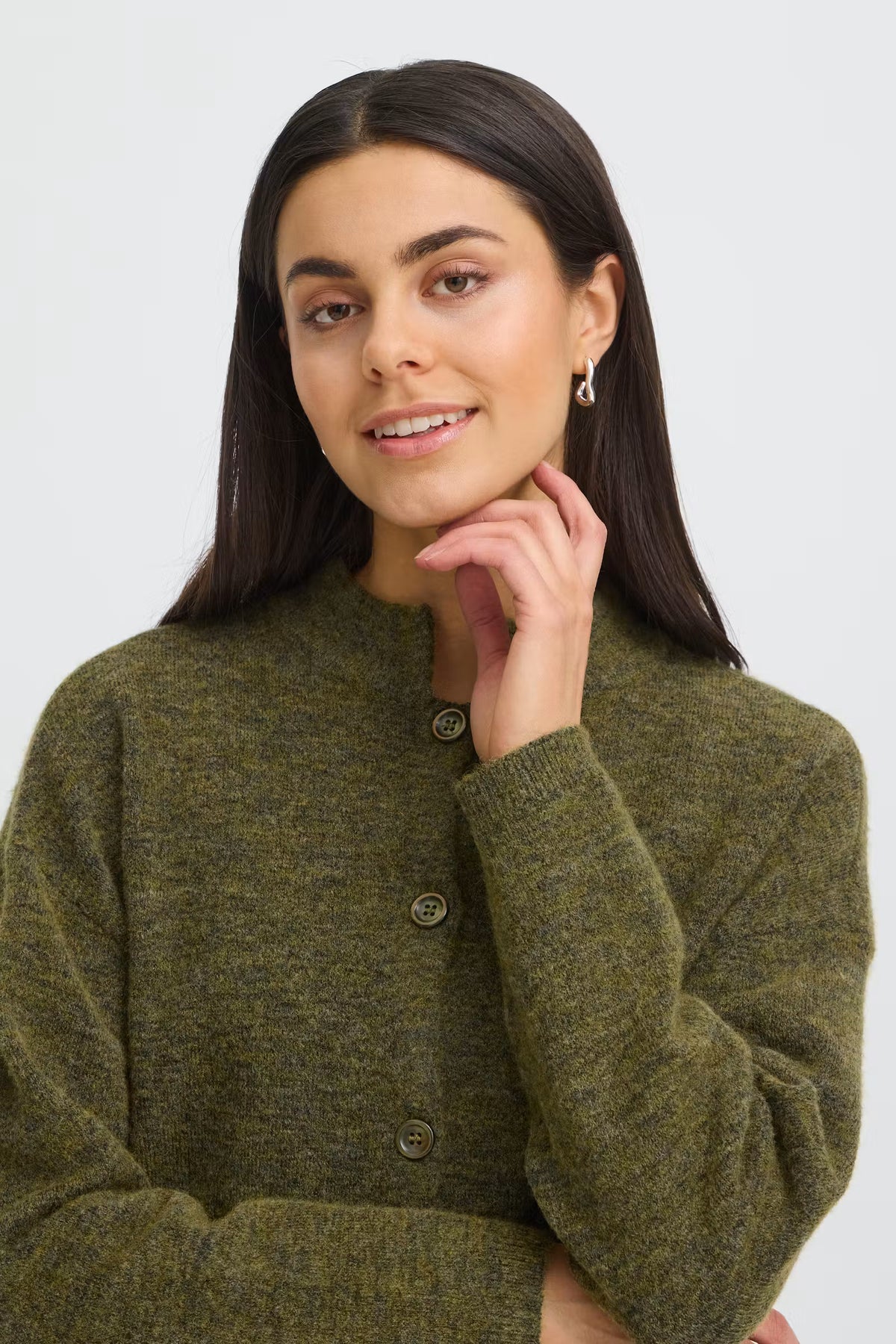 A woman wearing a textured olive green knit cardigan sweater with a buttoned front, shown against a plain light gray background.