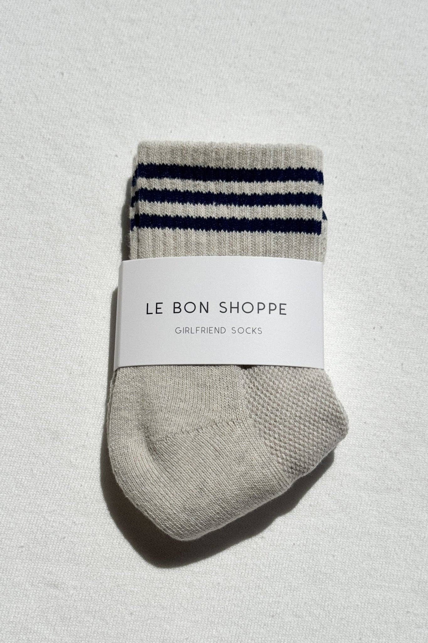 Folded gray socks with blue stripes and a white label on a textured light gray background