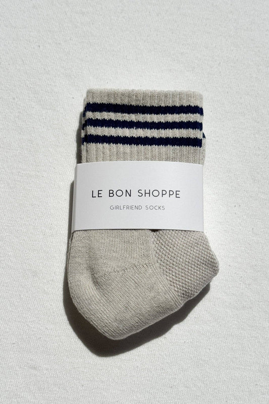 Folded gray socks with blue stripes and a white label on a textured light gray background