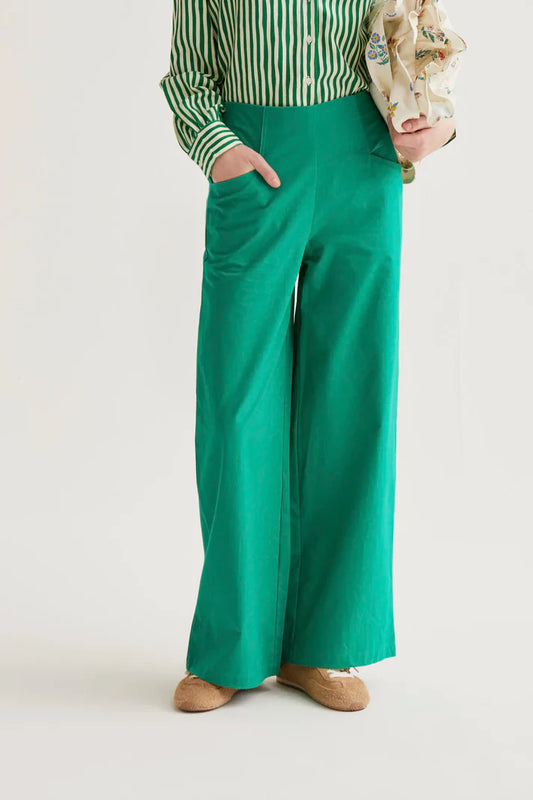 Person wearing green wide-leg pants with a white background