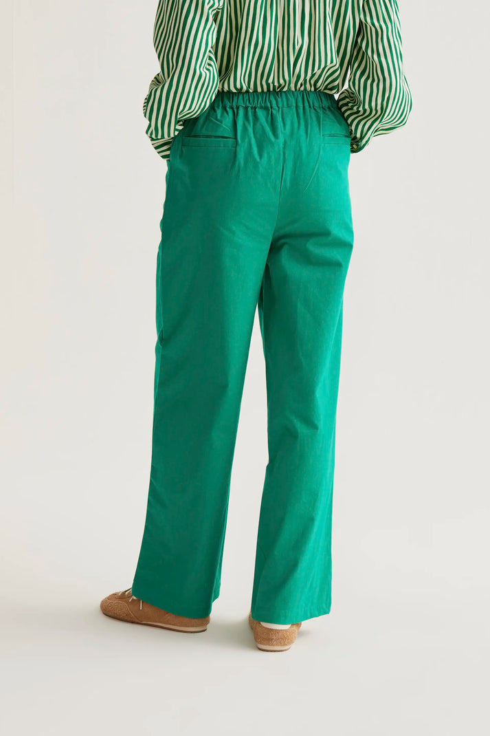 Person wearing green pants and a striped shirt on a plain background