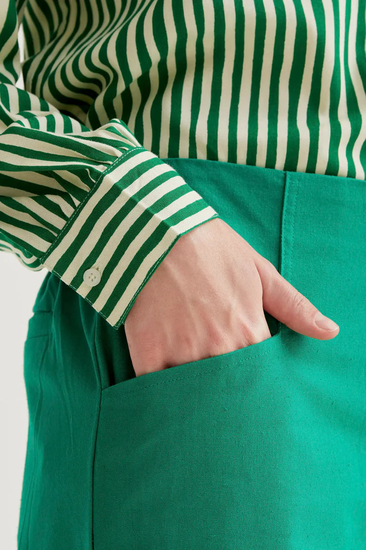 Person wearing a green and white striped shirt with a green apron.