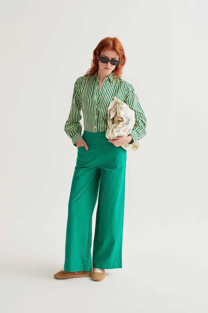 Person wearing a green striped shirt and green pants holding a bouquet on a white background
