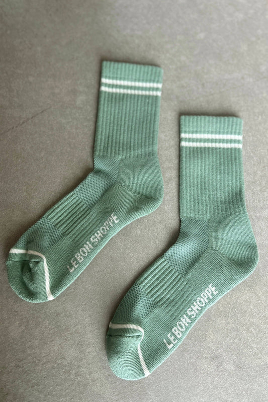 Green socks with white stripes and 'Le Bon Shoppe' branding on a gray background
