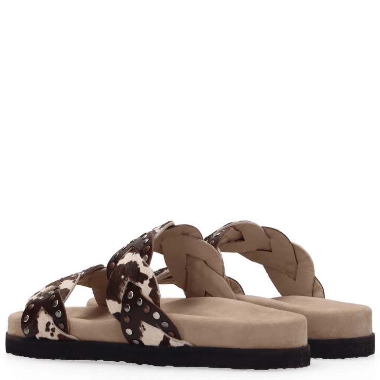 Pair of sandals with braided design and cow print on a white background