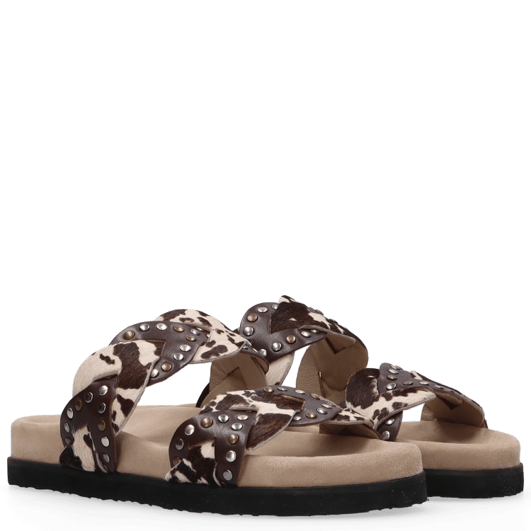 Pair of sandals with cow print straps on a white background