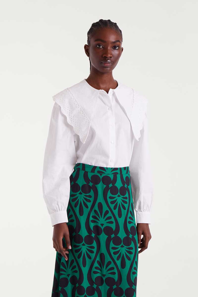 Woman wearing a white blouse and green patterned skirt on a white background