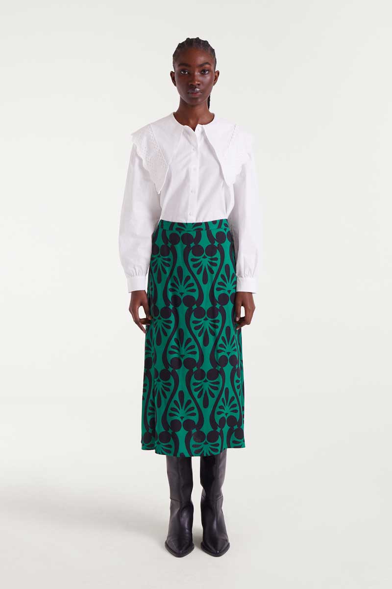 Person wearing a white blouse and green patterned skirt on a white background