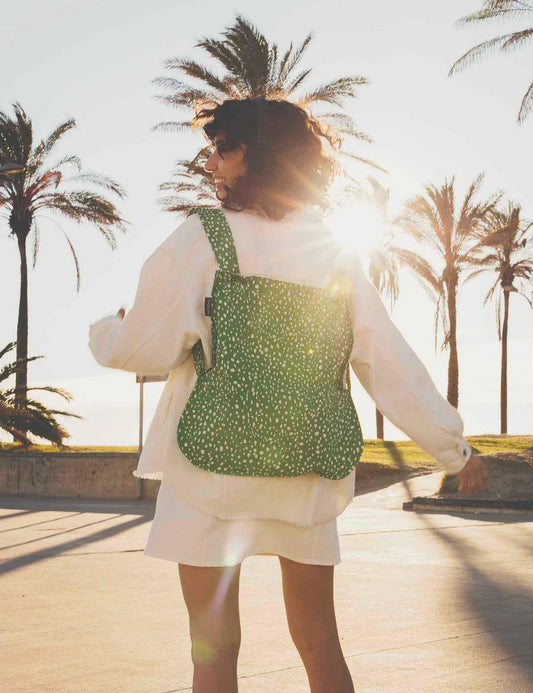 Person wearing a green polka dot. bag with palm trees in the background