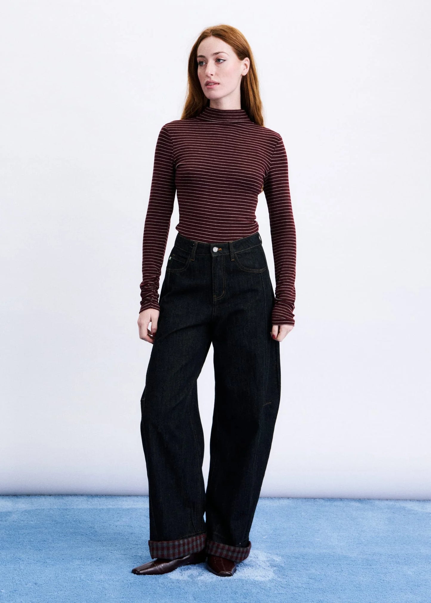 Woman wearing a striped long-sleeve top and black pants on a white background