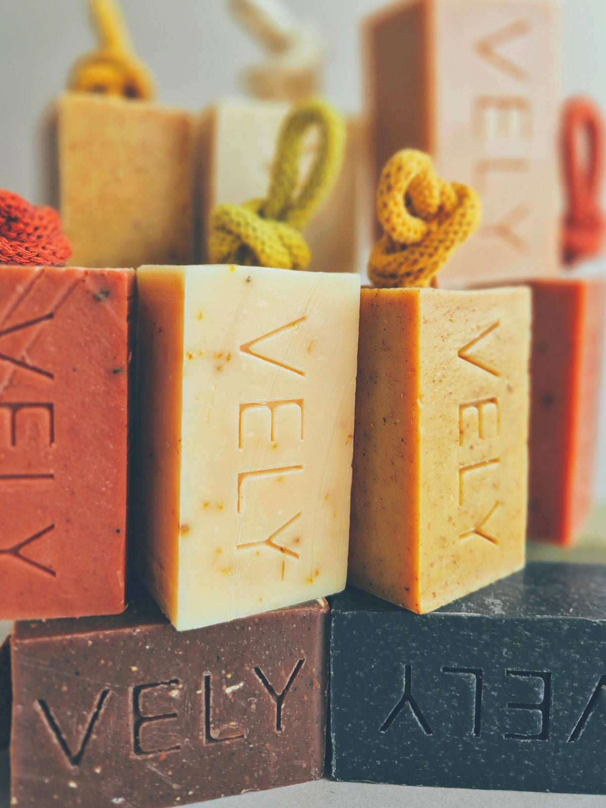 Assorted VELY soap bars in various colors with branding.