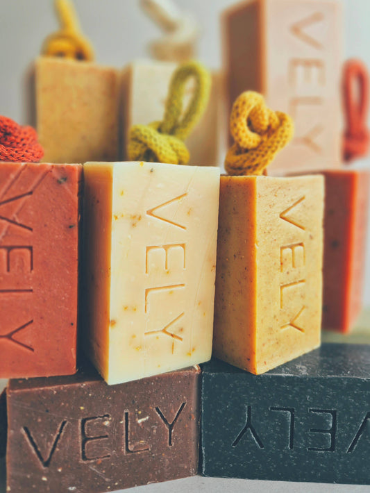 Assorted VELY soap bars in various colors with branding.