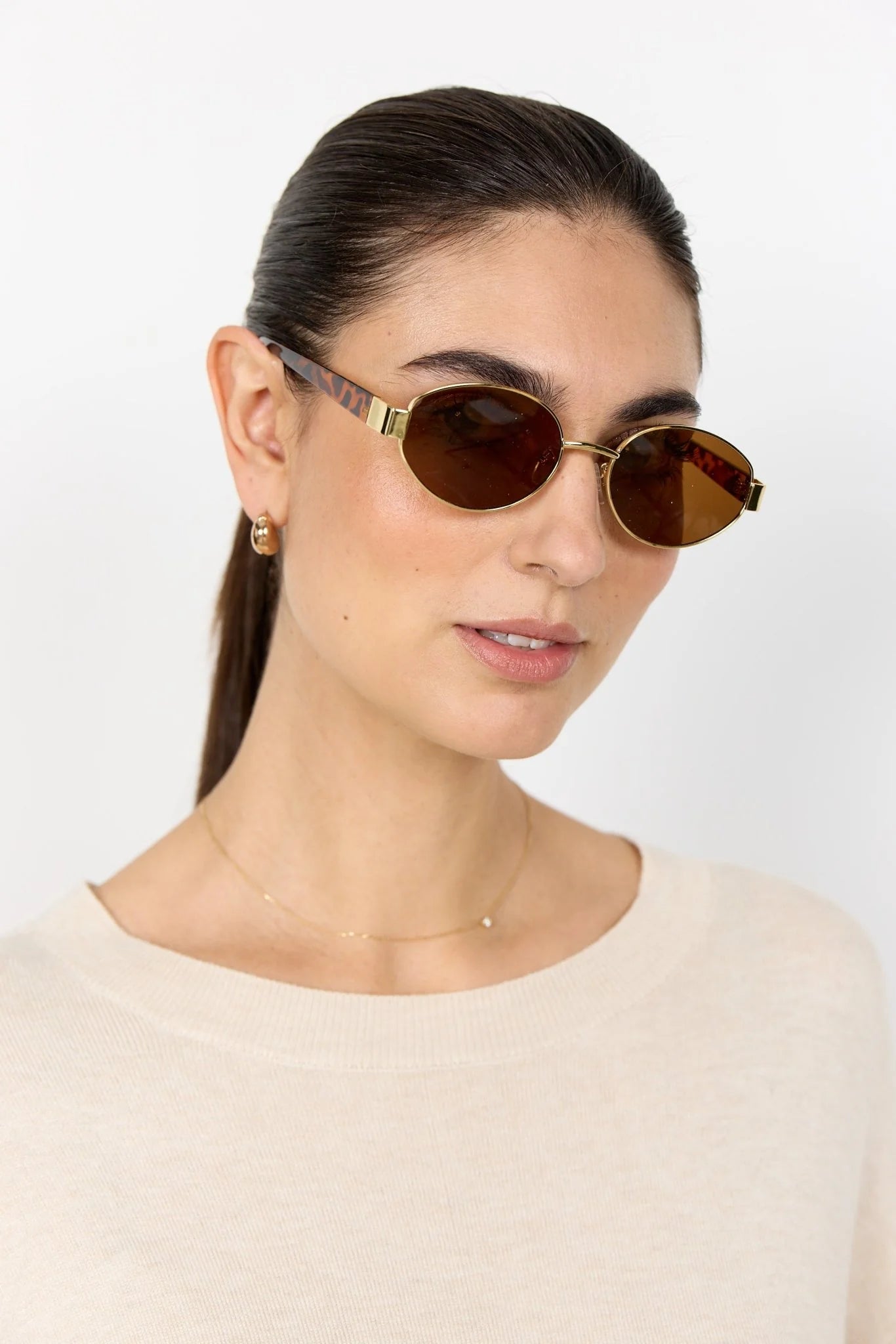 Woman wearing round sunglasses with a plain background