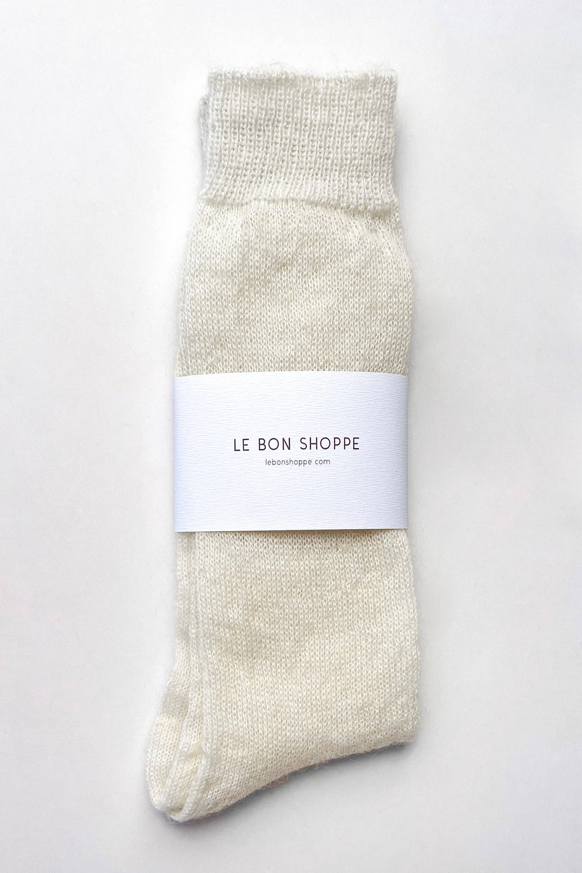 A single cream-colored knit sock with a white paper band label reading 'LE BON SHOPPE' on a clean white background.