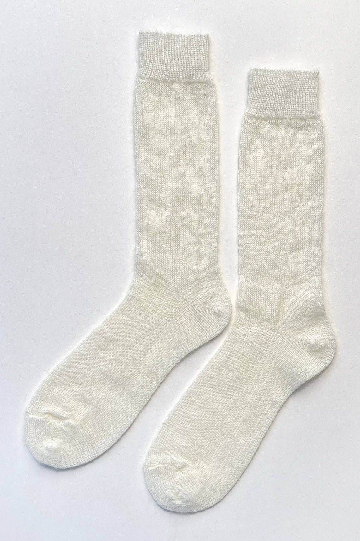 A pair of off-white, textured knit crew socks laid flat on a light gray background.