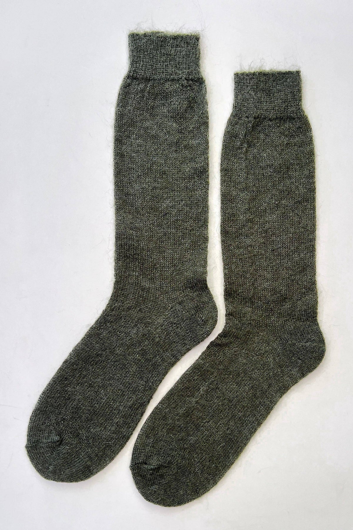 A pair of dark olive green knit socks laid flat on a white background.