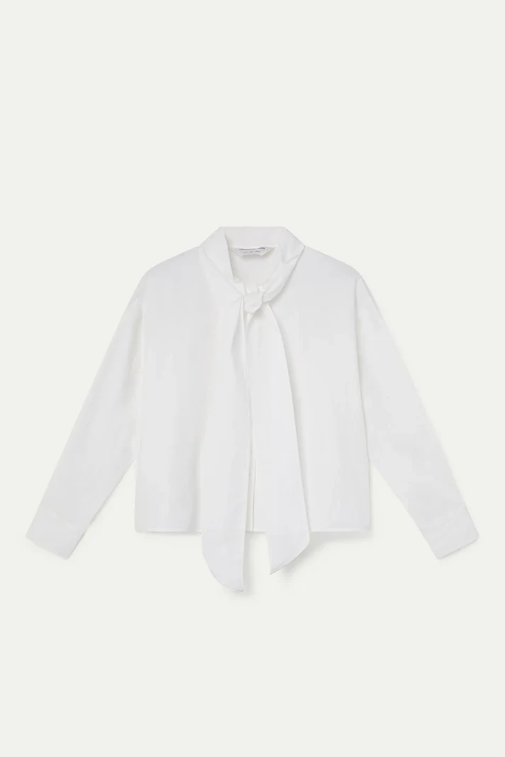 A white long-sleeve blouse with a wide collar and a self-tie neck scarf, laid flat against a light off-white background.