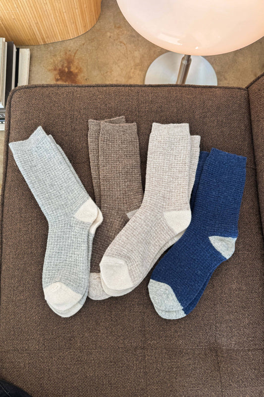 Four pairs of socks in gray and blue on a brown surface