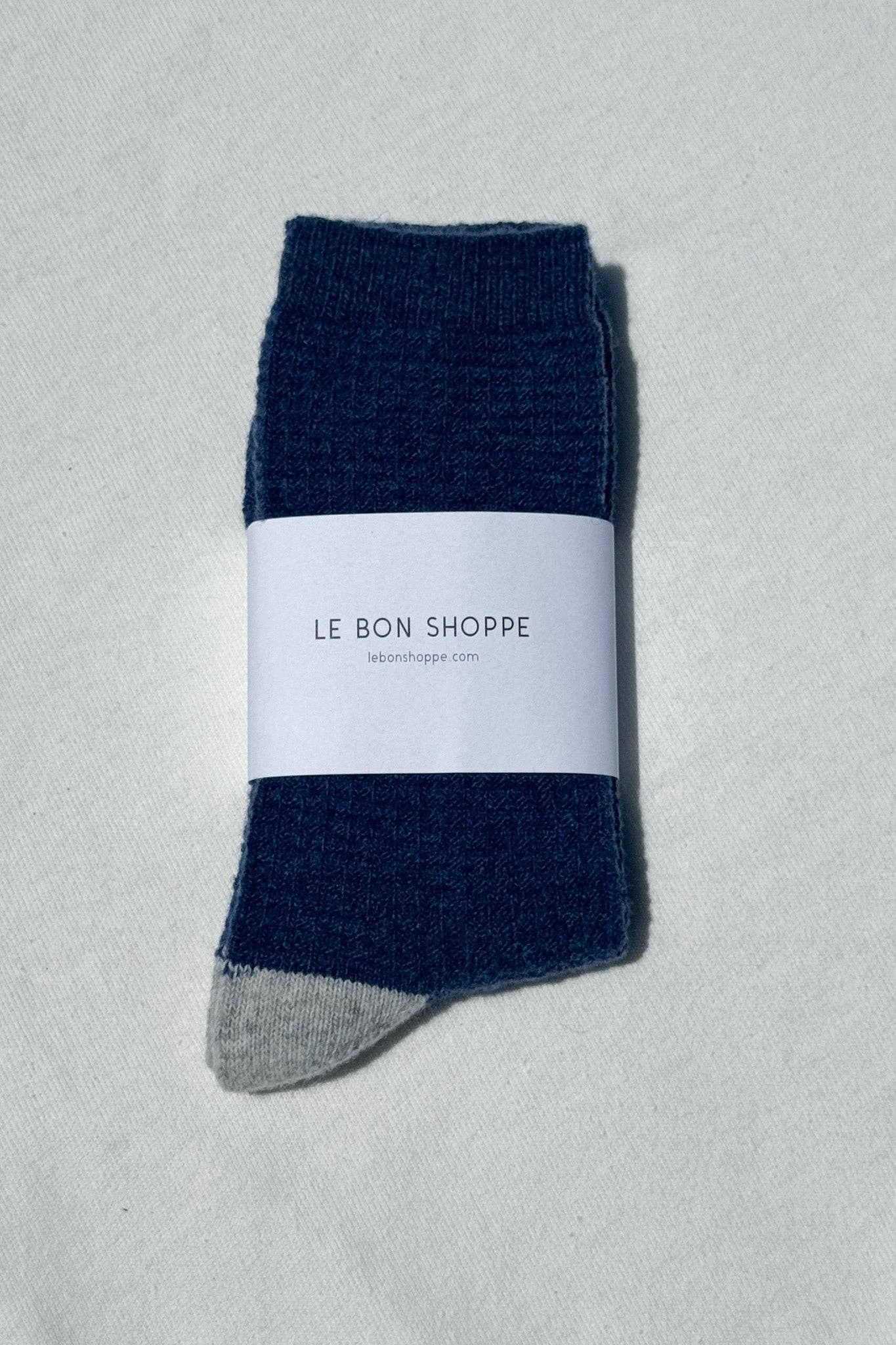 Navy blue sock with gray heel and toe on a light gray background, featuring 'Le Bon Shoppe' label.
