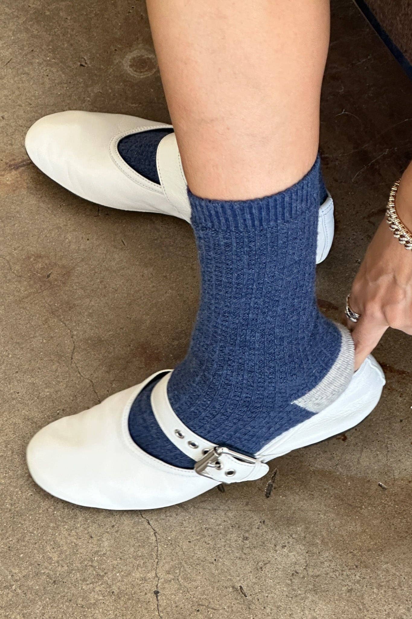 Person wearing blue socks with white shoes on a brown surface