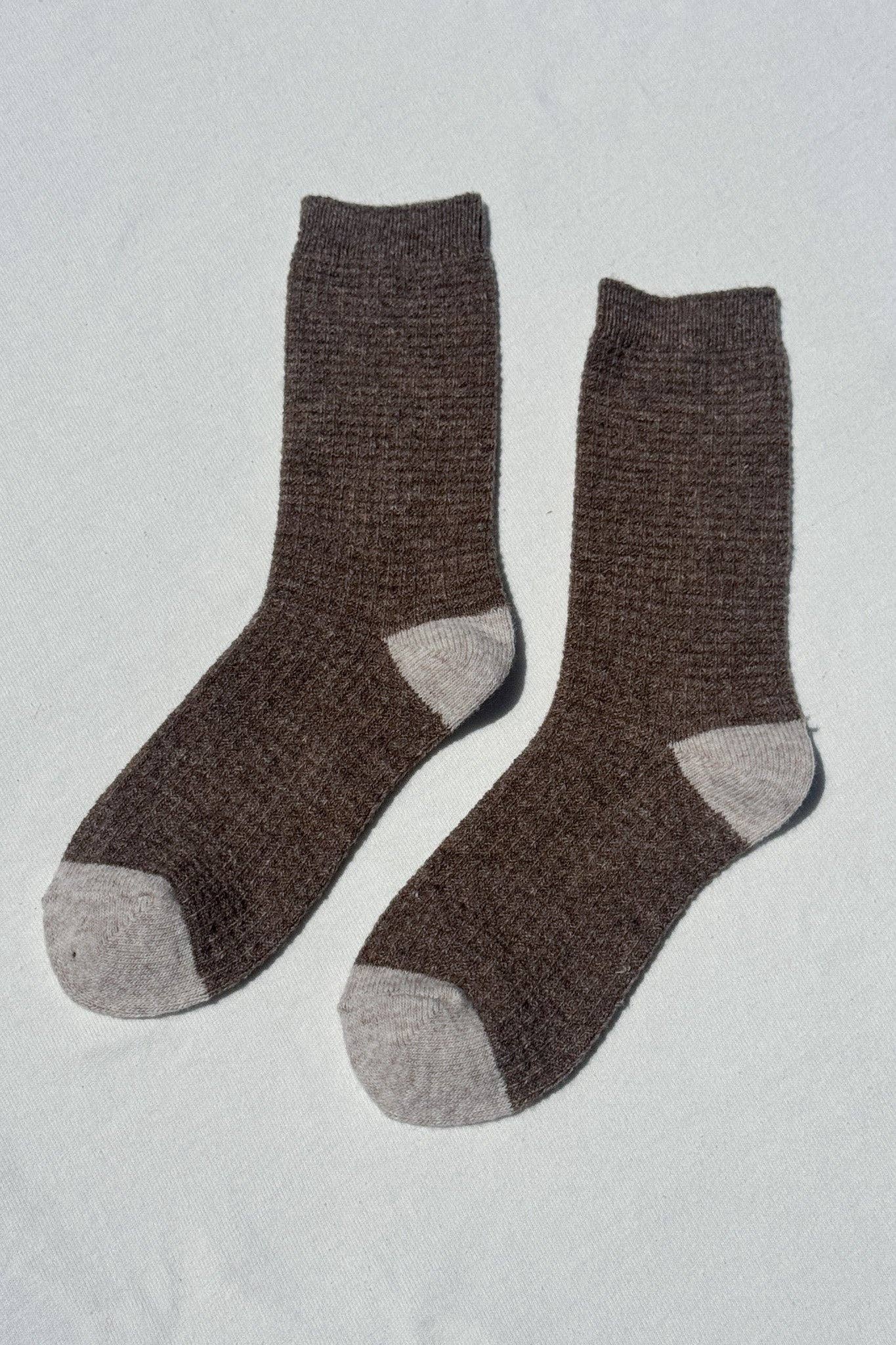 Pair of brown socks with gray toes and cuffs on a light gray background