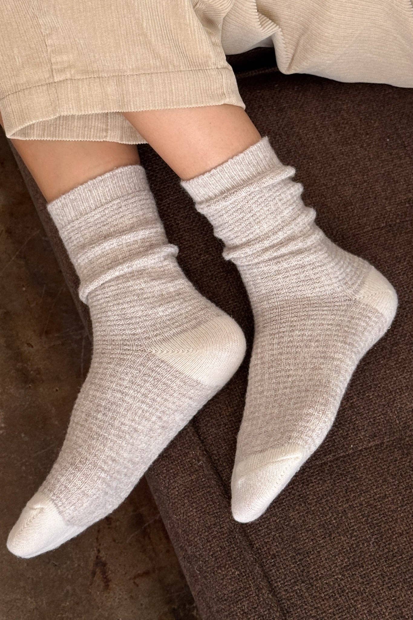 White socks worn on a person's feet with a brown background